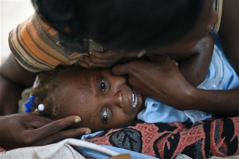 A child suffering cholera symptoms cries as she is comforted by a woman at a hospital in Grande-Saline, Haiti, on Saturday. 